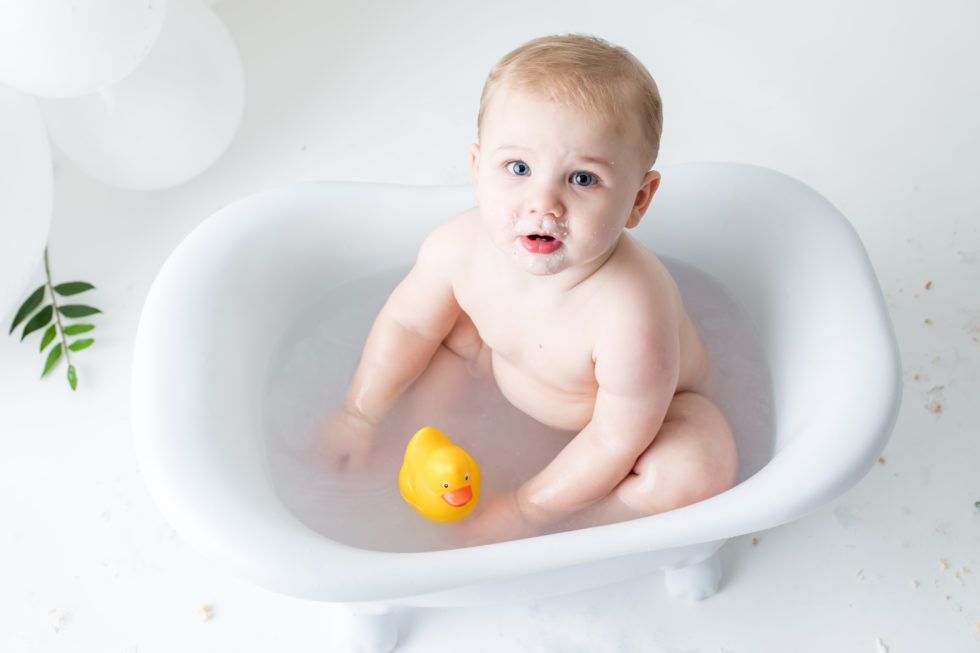 baby sits in little bathtub with yellow ducky