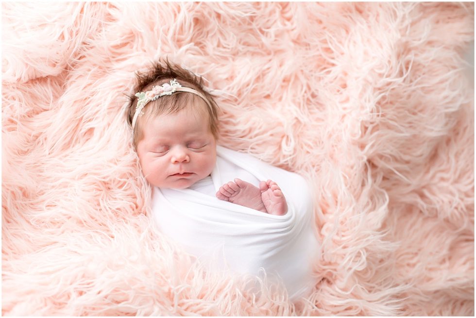 newborn baby girl bundled on pink shag rug