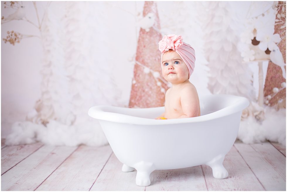 baby girl with blue eyes has bath in cute little tub