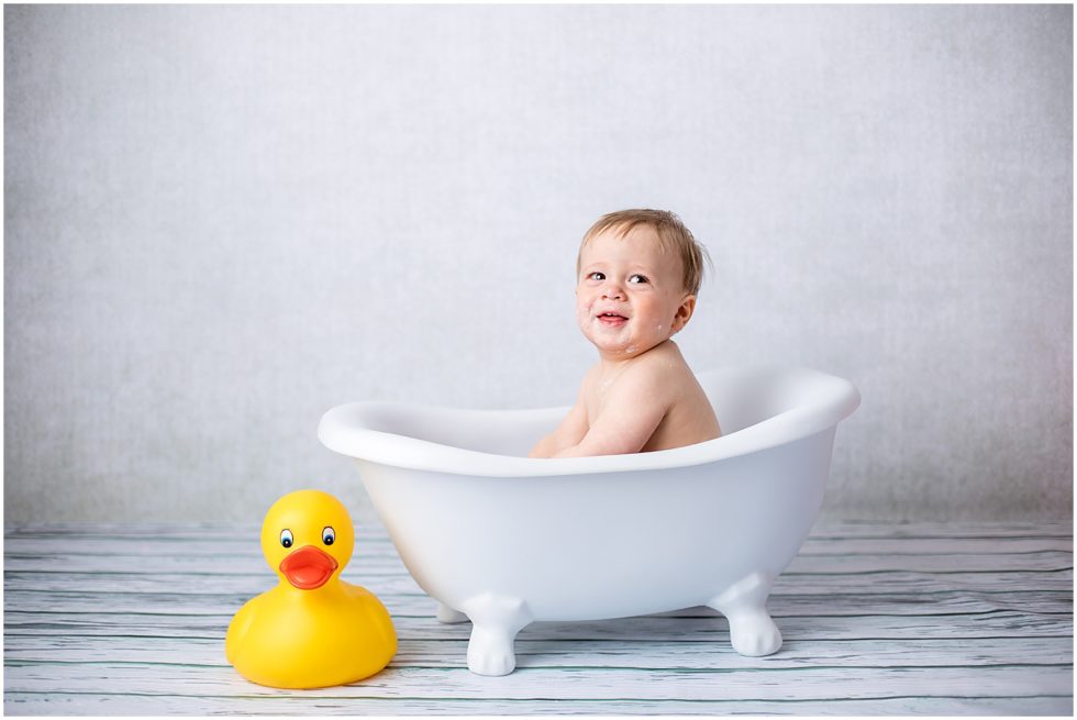 boy sits in tiny bath with giant yellow duck