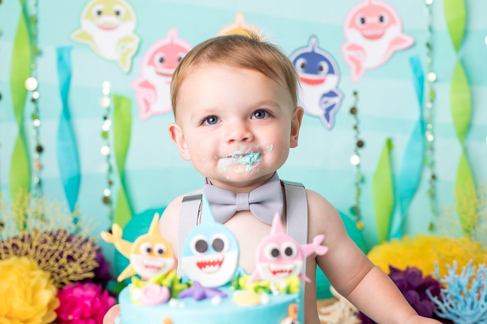One-year-old baby boy eats baby shark cake during cake smash session