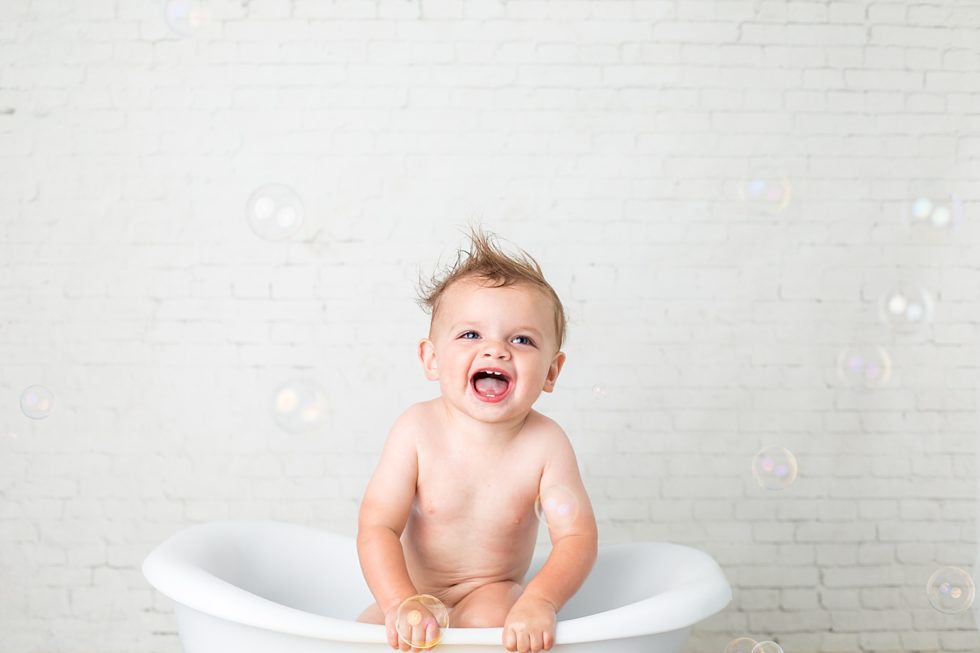 little boy laughs at bubbles in tub
